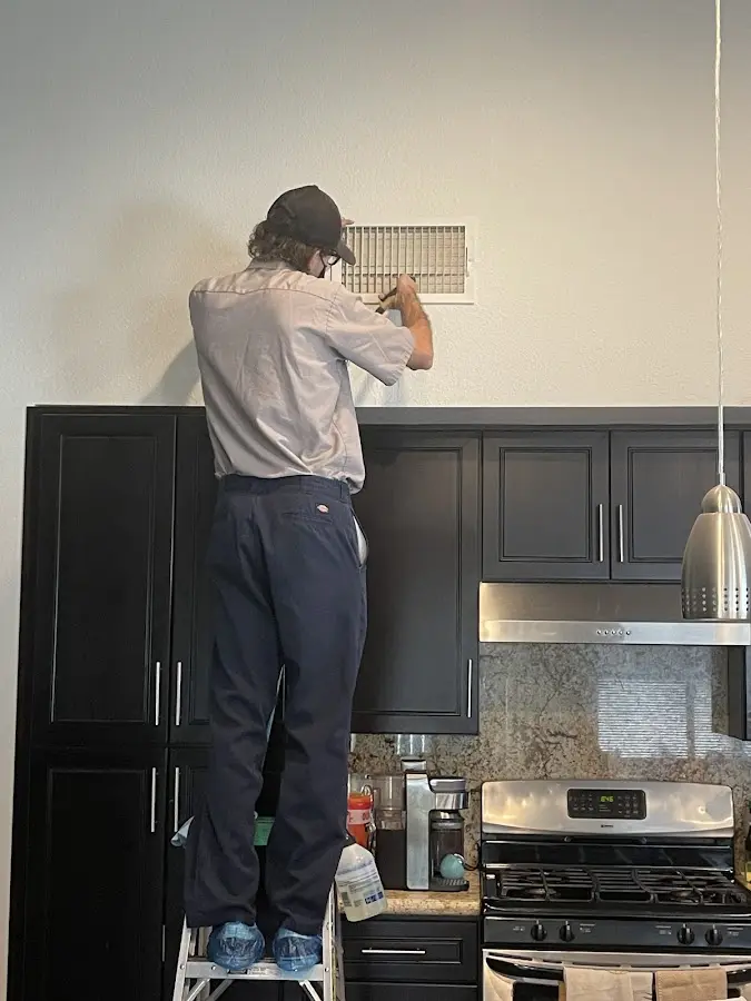 Technician inspecting an air vent during HVAC service in Sun Valley